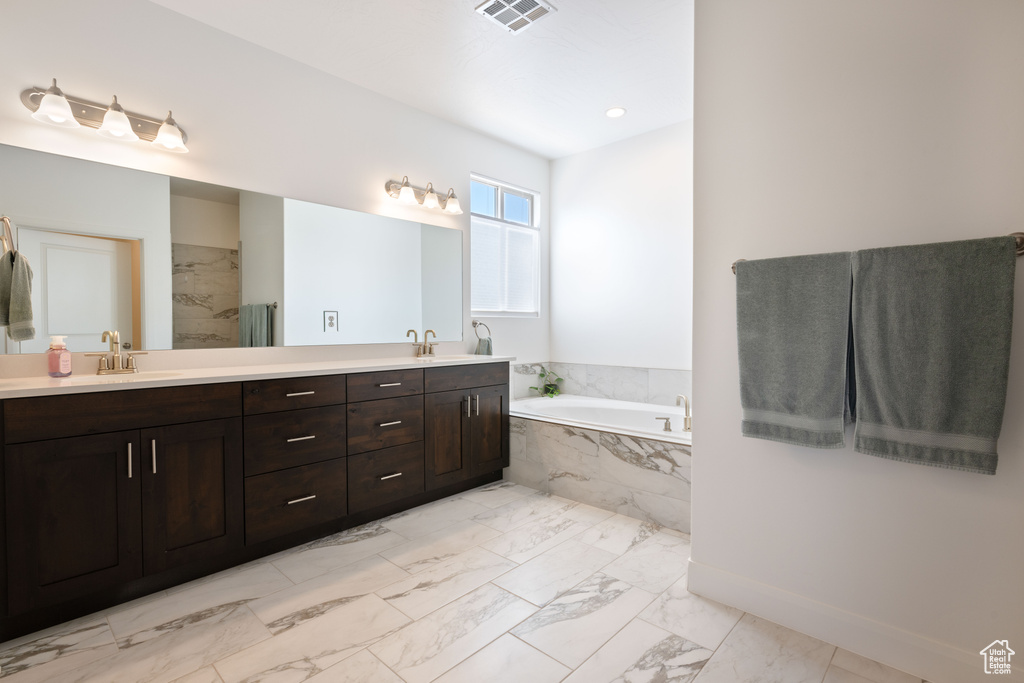 Bathroom featuring tile patterned floors, double vanity, and tiled bath