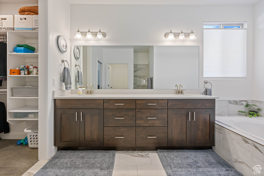 Bathroom featuring tile patterned flooring, tiled bath, and dual vanity