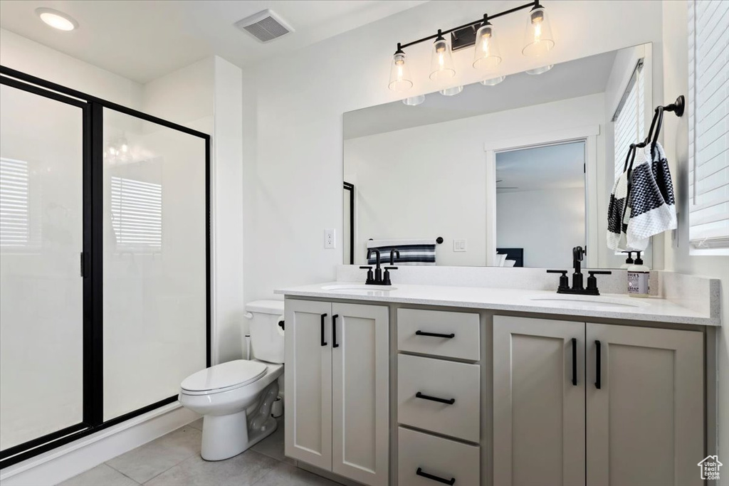 Bathroom featuring dual bowl vanity, walk in shower, tile patterned flooring, and toilet