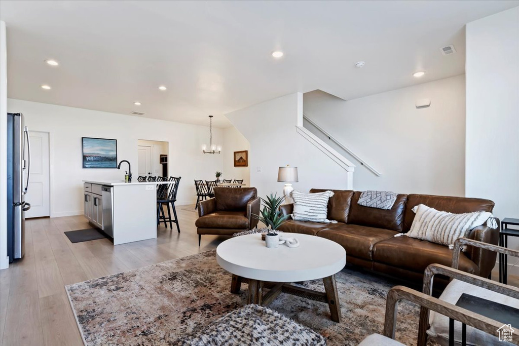 Living room featuring a notable chandelier, light wood-type flooring, and sink