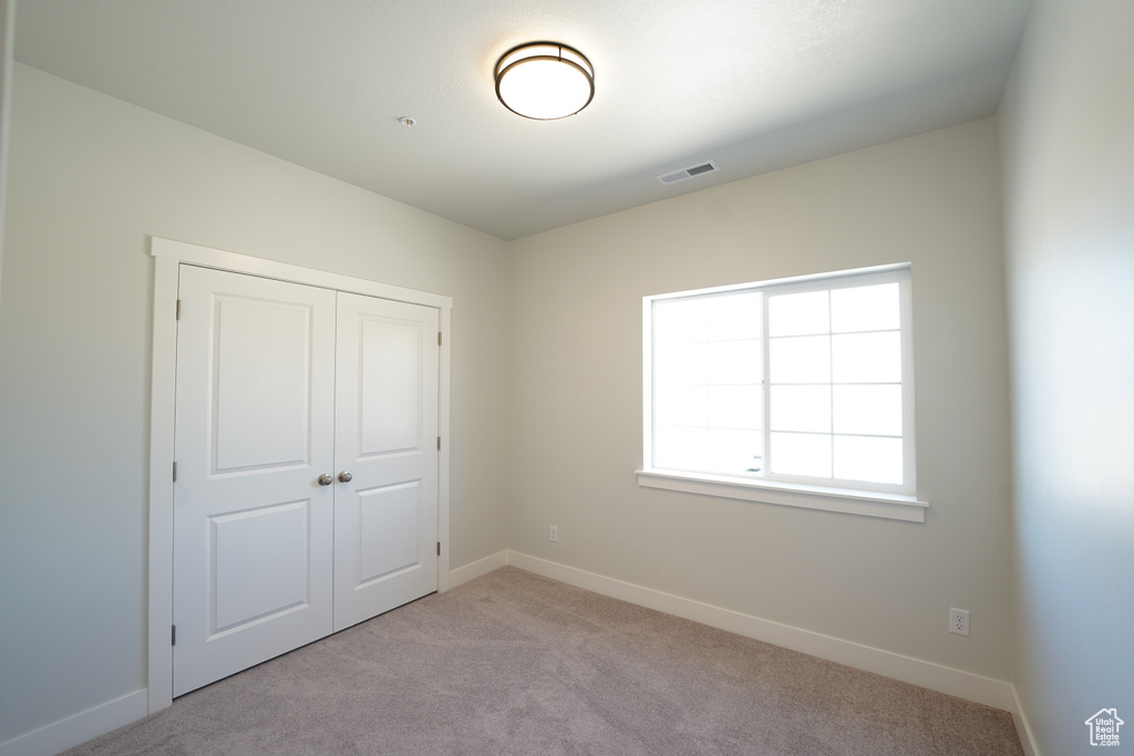 Unfurnished bedroom with a closet and light carpet