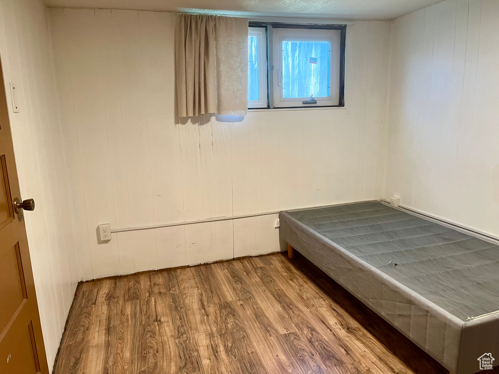 Unfurnished bedroom featuring wood-type flooring and wooden walls