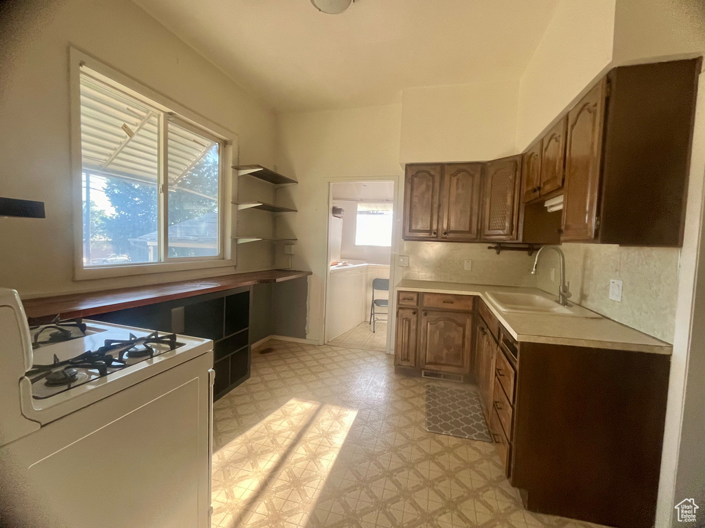 Kitchen with decorative backsplash, white gas range oven, and sink