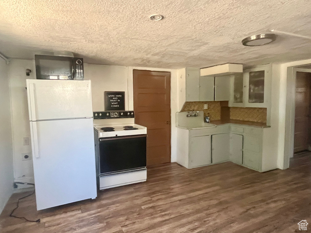 Kitchen featuring white appliances, sink, dark hardwood / wood-style floors, tasteful backsplash, and a textured ceiling