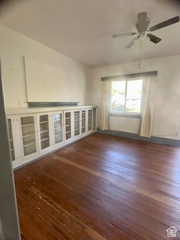 Empty room with ceiling fan and dark hardwood / wood-style flooring