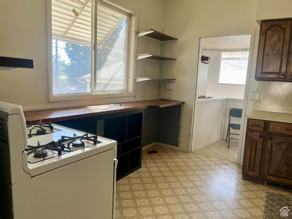 Kitchen featuring plenty of natural light, white range with gas cooktop, and dark brown cabinets