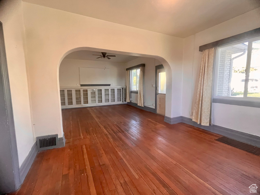 Unfurnished living room featuring a wealth of natural light, ceiling fan, and hardwood / wood-style floors