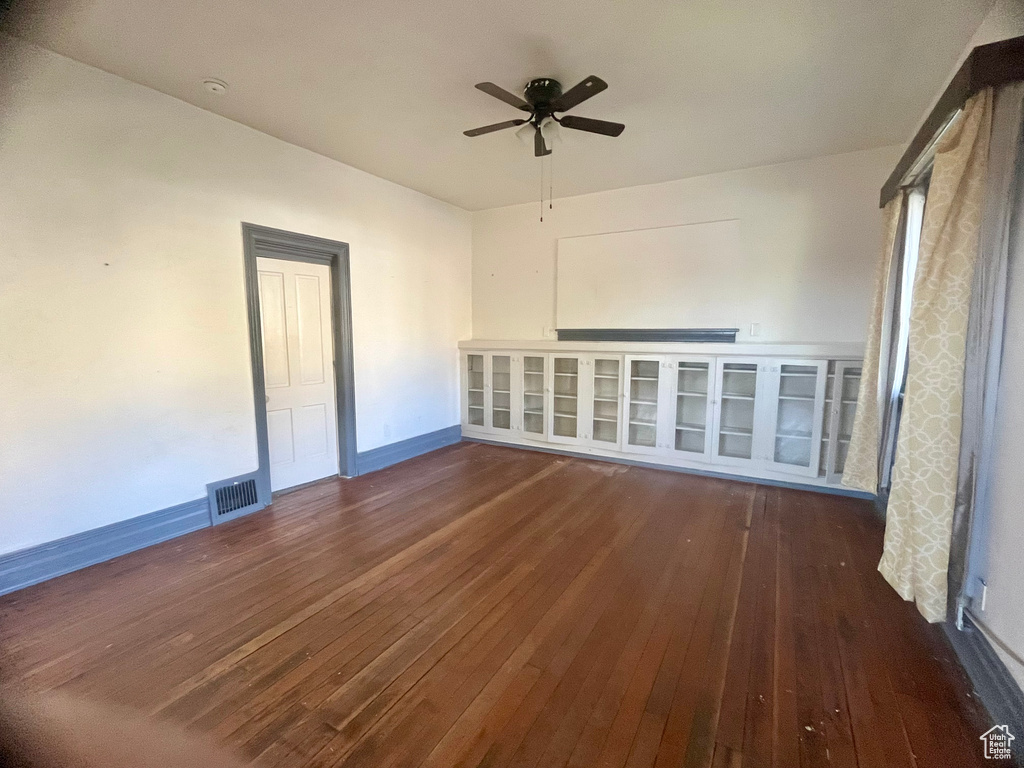 Unfurnished room with dark wood-type flooring and ceiling fan