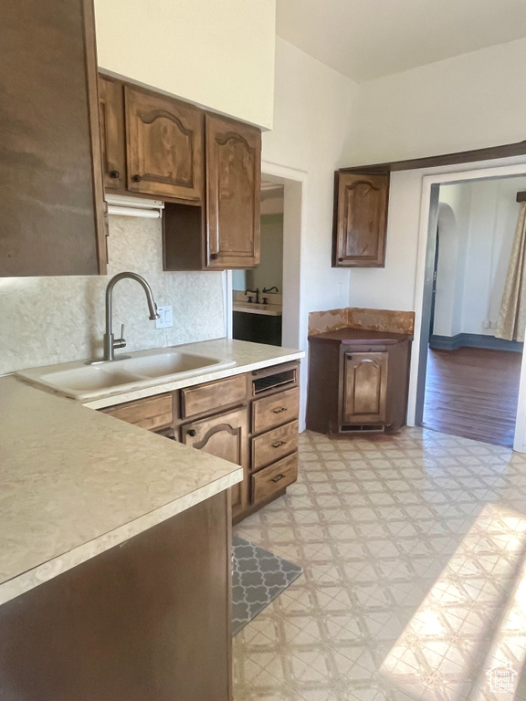 Kitchen featuring light wood-type flooring, sink, and decorative backsplash