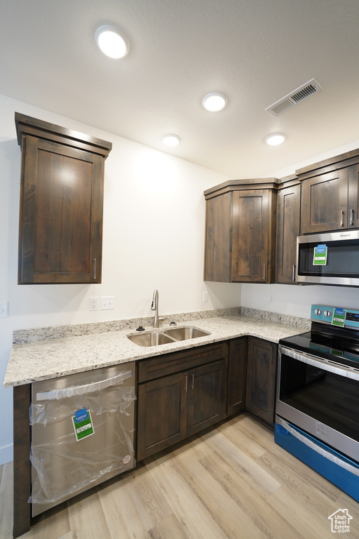 Kitchen with light wood-type flooring, sink, stainless steel appliances, and dark brown cabinets