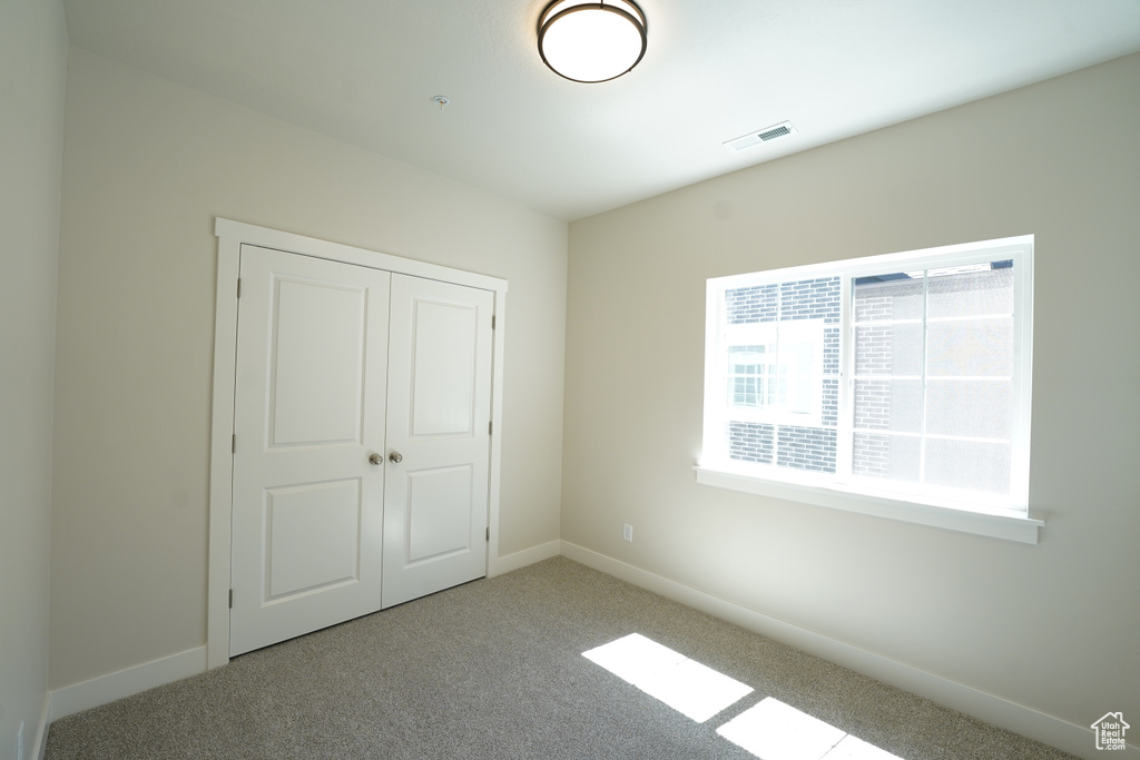 Unfurnished bedroom featuring a closet and light carpet