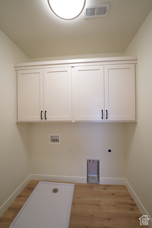 Laundry area featuring hookup for an electric dryer, washer hookup, light hardwood / wood-style floors, and cabinets