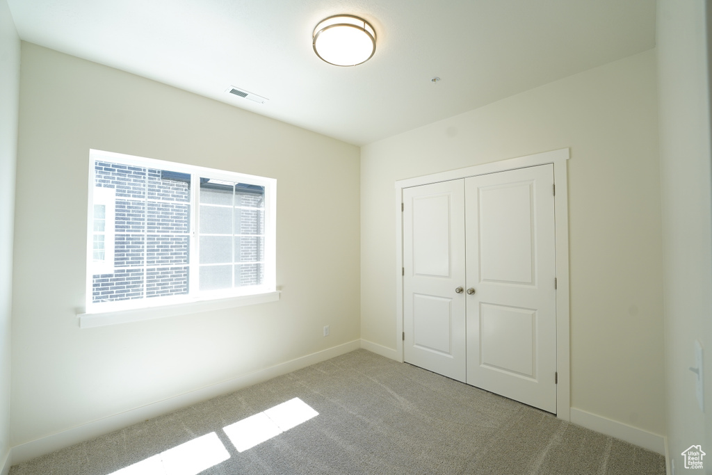 Unfurnished bedroom featuring a closet and light colored carpet