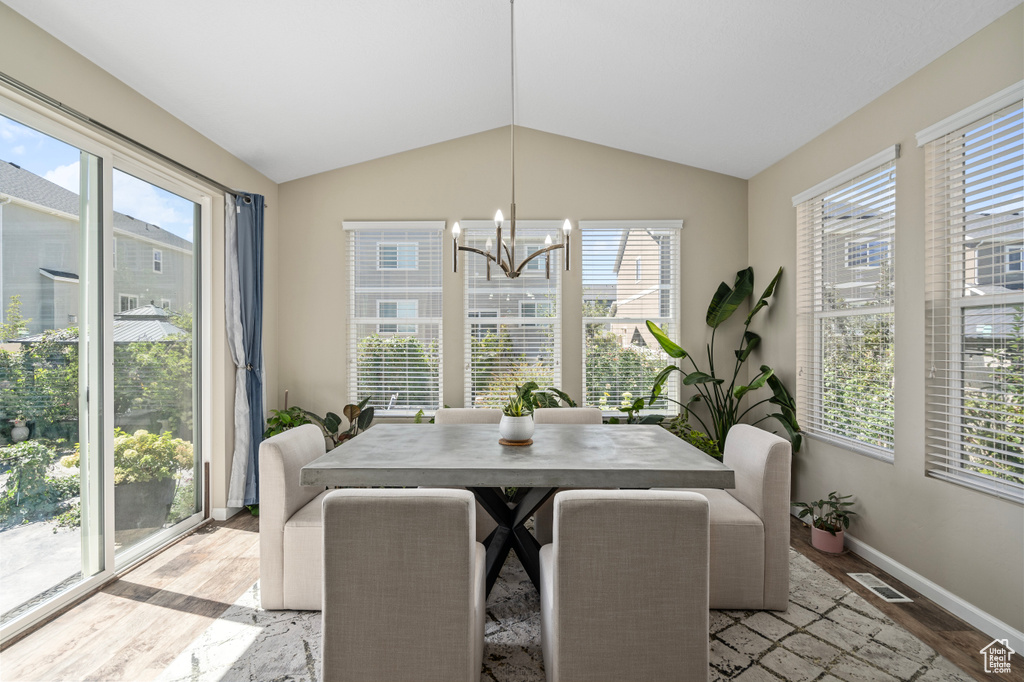 Dining area featuring an inviting chandelier, light hardwood / wood-style flooring, and lofted ceiling