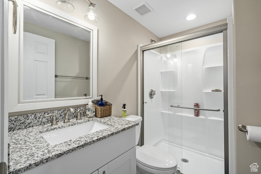 Bathroom featuring vanity, walk in shower, and toilet