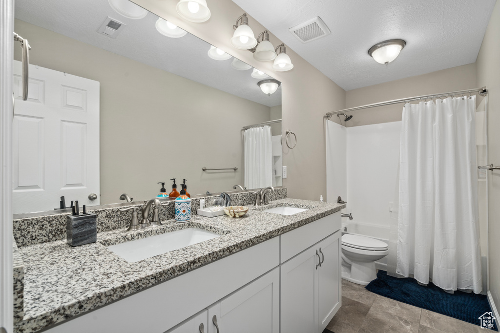 Full bathroom with shower / bathtub combination with curtain, toilet, double vanity, and tile patterned floors