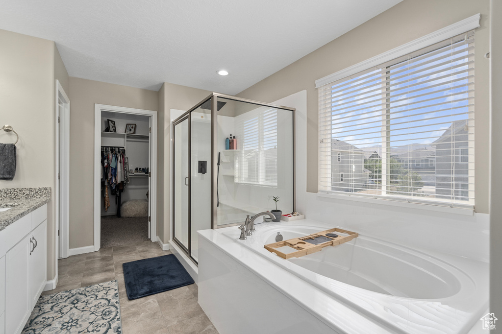 Bathroom featuring shower with separate bathtub, tile patterned floors, and vanity