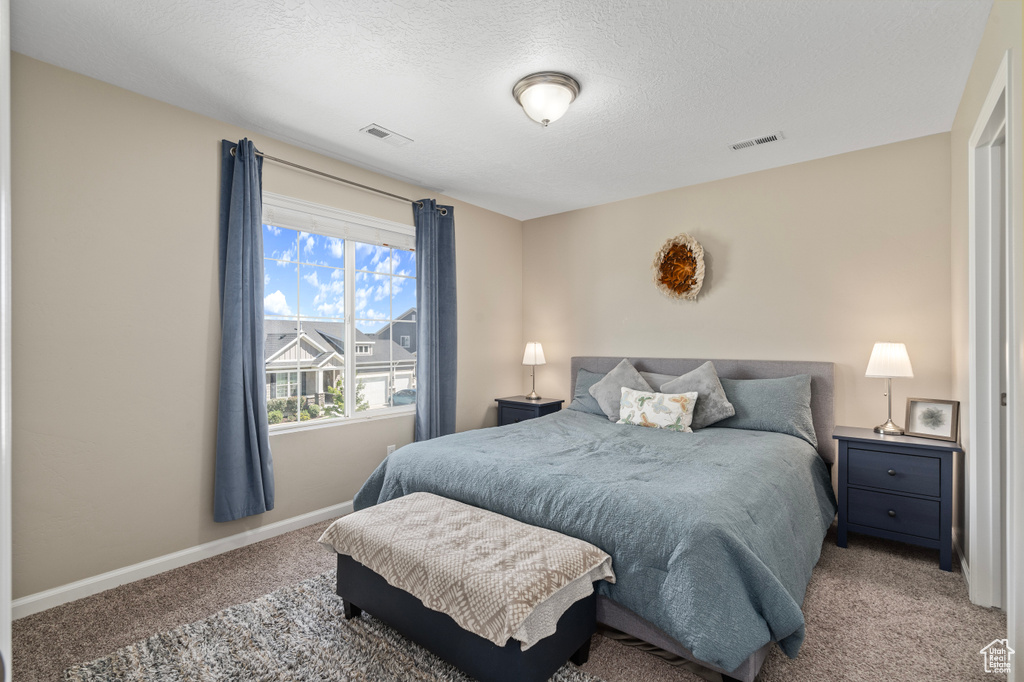 Bedroom with a textured ceiling and light carpet