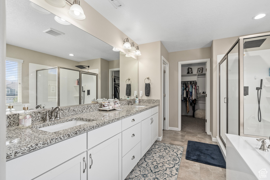 Bathroom with tile patterned floors, double vanity, and a shower with shower door