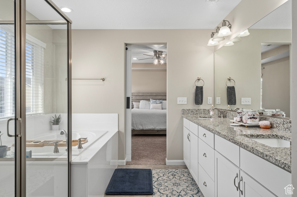 Bathroom featuring ceiling fan, a tub, double sink vanity, and tile patterned flooring