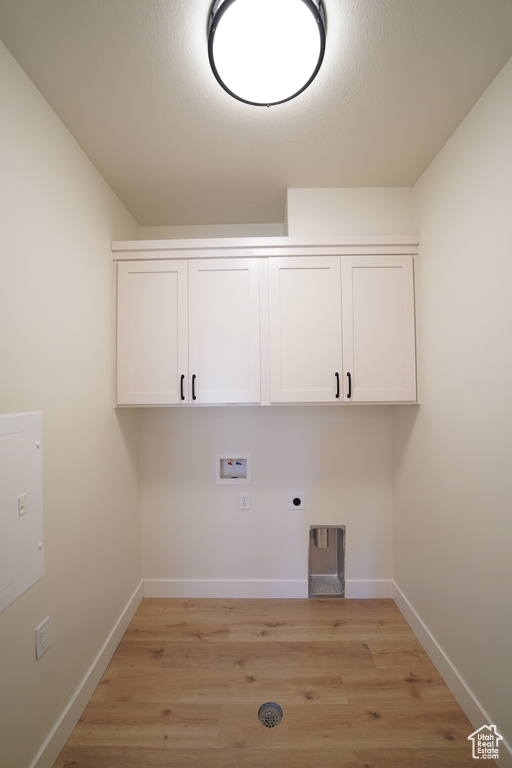 Laundry area featuring electric dryer hookup, light hardwood / wood-style floors, hookup for a washing machine, and cabinets