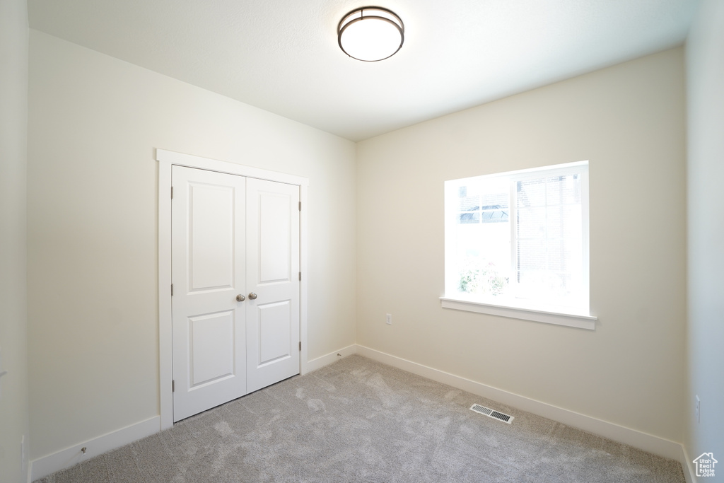 Unfurnished bedroom with a closet and light colored carpet