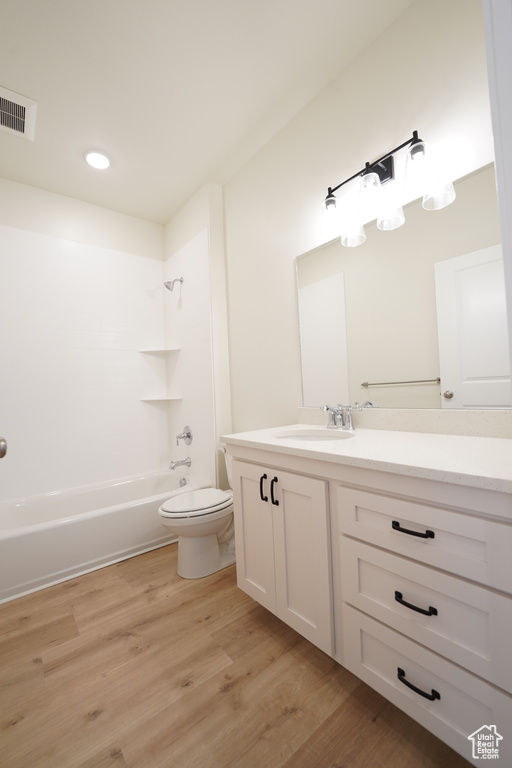 Full bathroom with shower / tub combination, vanity, hardwood / wood-style floors, and toilet