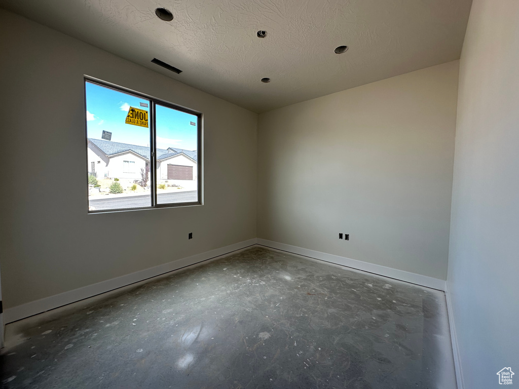 Unfurnished room featuring a textured ceiling and concrete flooring