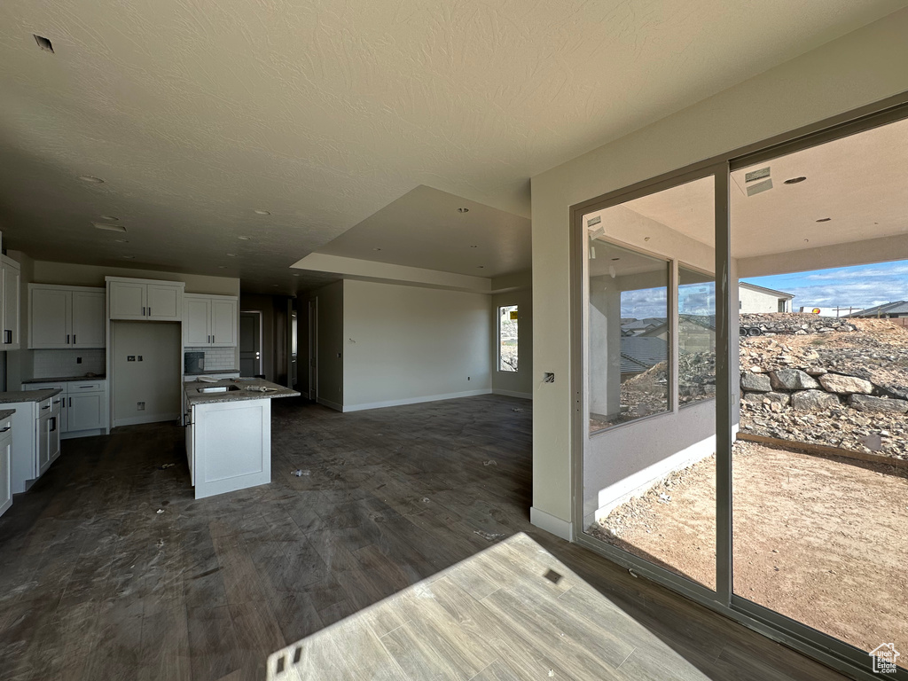 Kitchen featuring white cabinets, a center island, dark wood-type flooring, and a textured ceiling