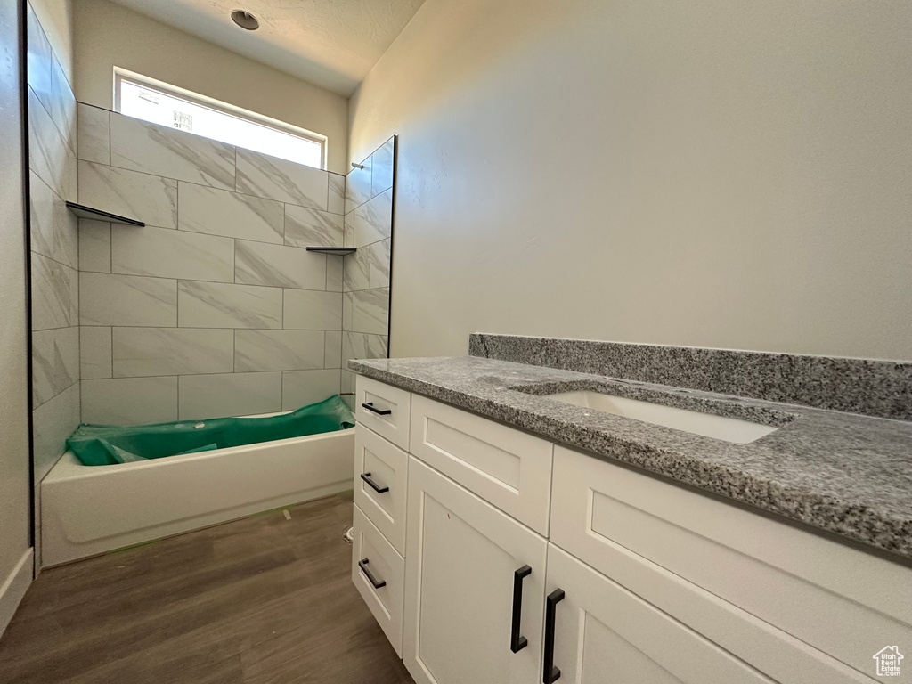 Bathroom featuring vanity, tiled shower / bath combo, and wood-type flooring