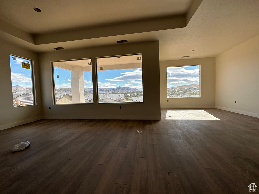 Unfurnished room featuring dark hardwood / wood-style floors, a healthy amount of sunlight, and a raised ceiling