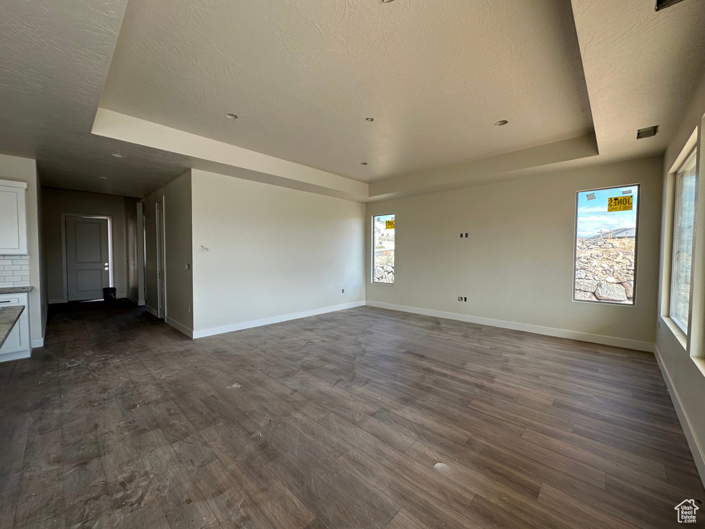 Unfurnished room with a tray ceiling, a textured ceiling, and dark hardwood / wood-style flooring