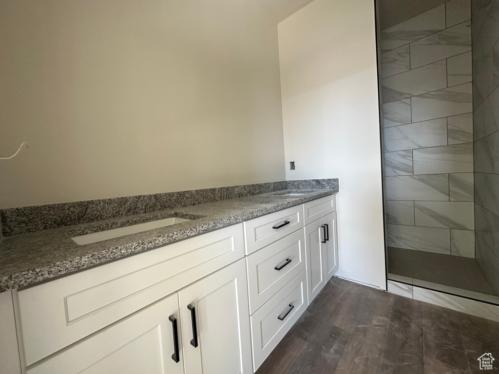 Bathroom featuring vanity, wood-type flooring, and tiled shower