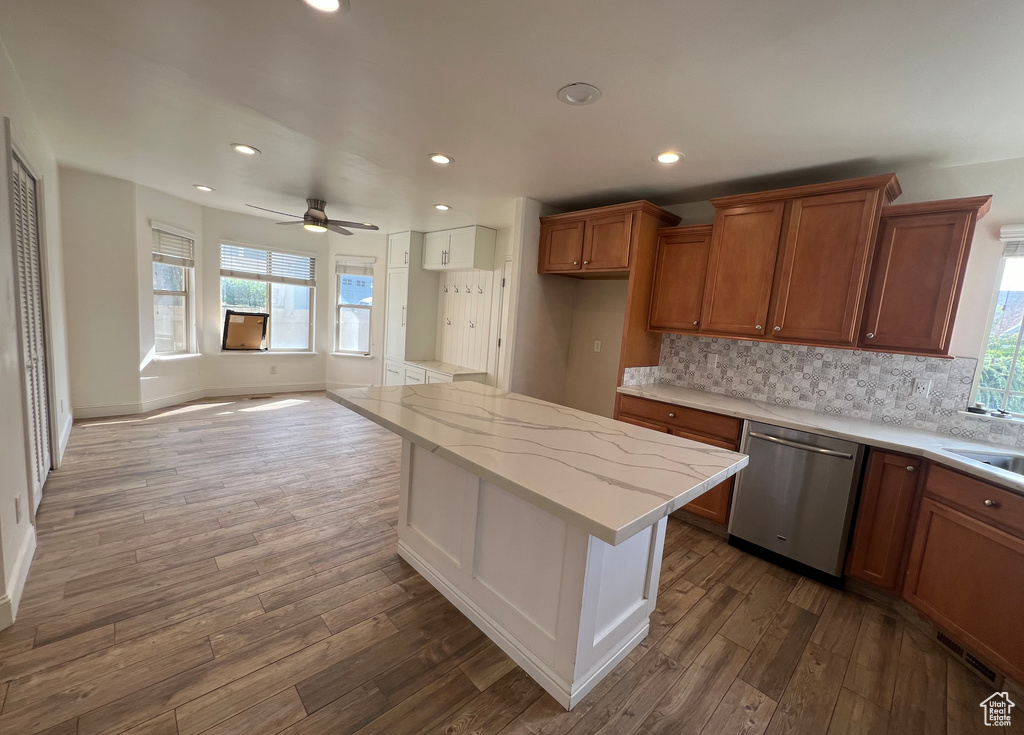 Kitchen featuring decorative backsplash, stainless steel dishwasher, dark hardwood / wood-style floors, a kitchen island, and ceiling fan