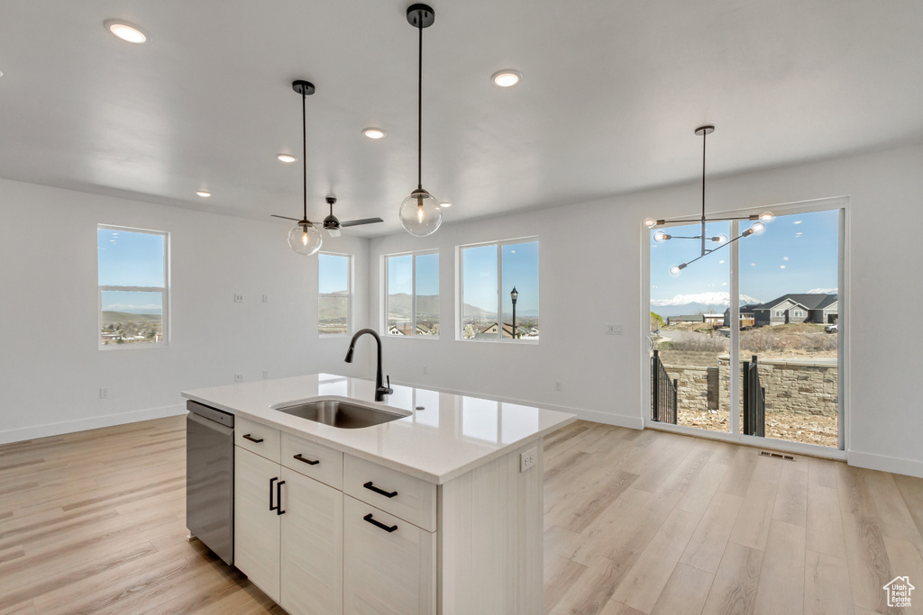 Kitchen featuring a kitchen island with sink, white cabinets, light hardwood / wood-style floors, dishwasher, and sink