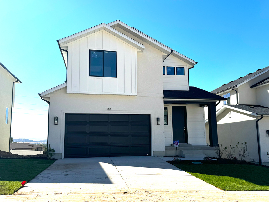 View of front of property with a garage and a front lawn