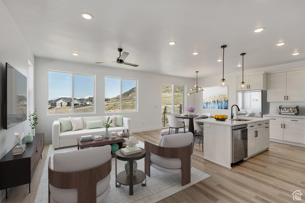 Living room with ceiling fan, light hardwood / wood-style floors, and sink