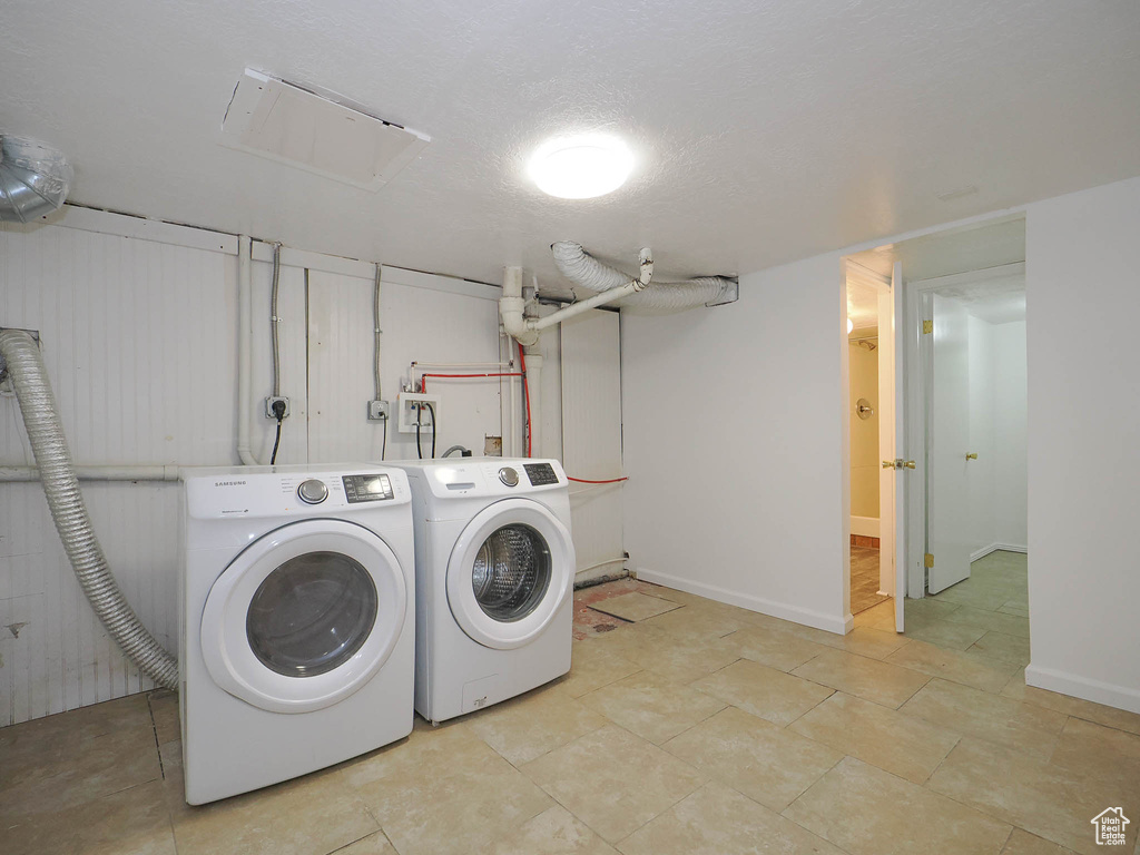 Clothes washing area with washer and clothes dryer and light tile patterned floors