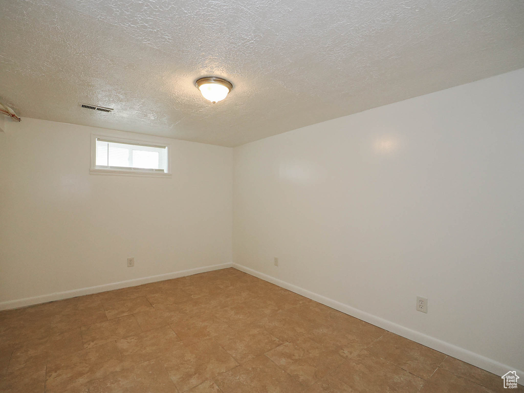 Basement featuring a textured ceiling and tile patterned flooring