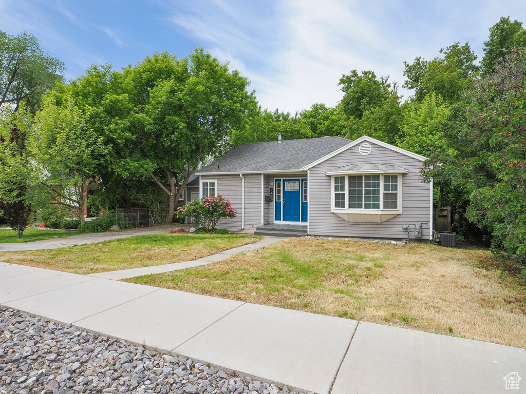 Single story home featuring central air condition unit and a front lawn