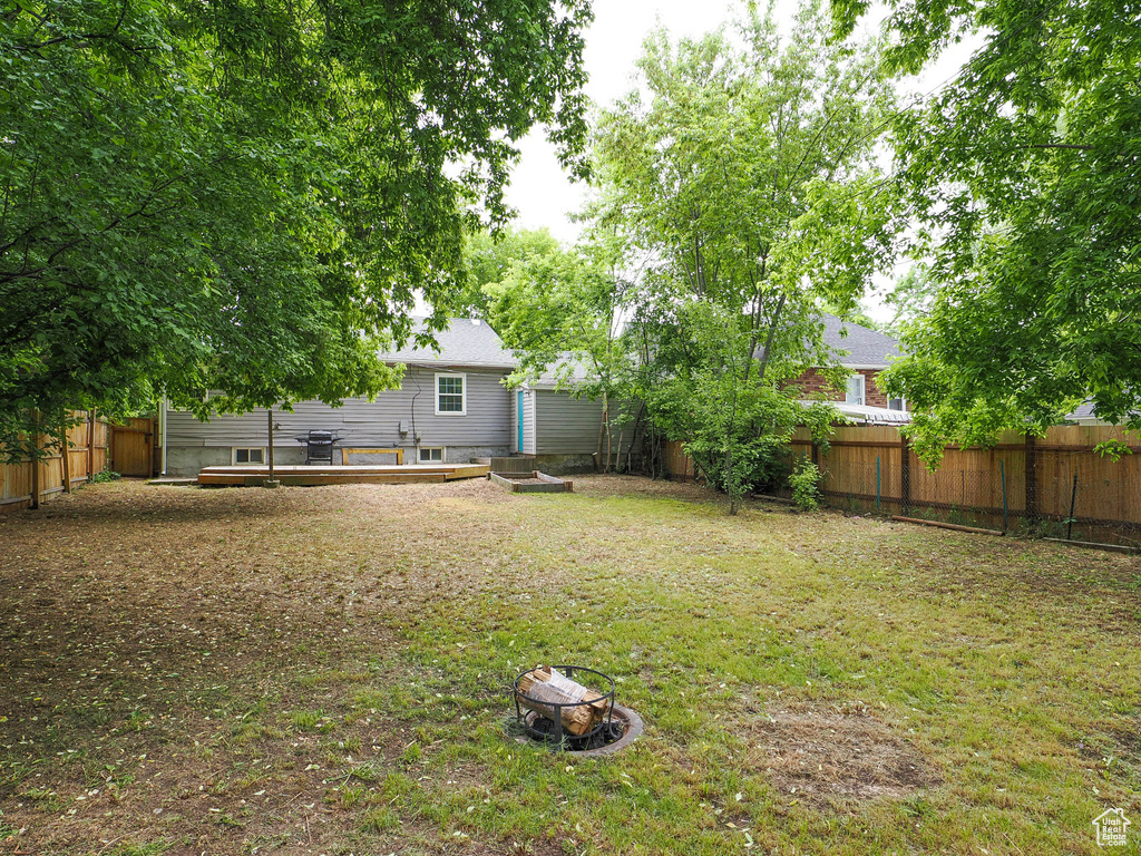 View of yard with a wooden deck and a fire pit