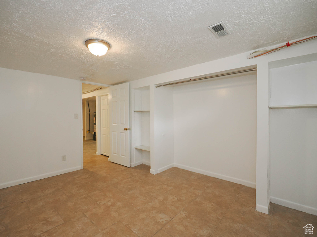 Interior space with a textured ceiling, a closet, and light tile patterned floors