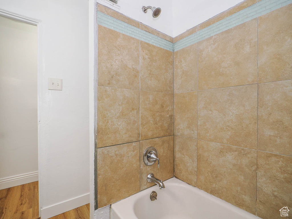 Bathroom with hardwood / wood-style flooring and tiled shower / bath