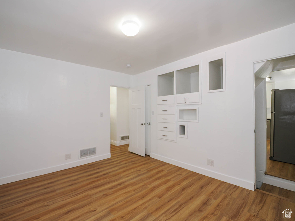 Unfurnished bedroom featuring stainless steel fridge and light hardwood / wood-style floors