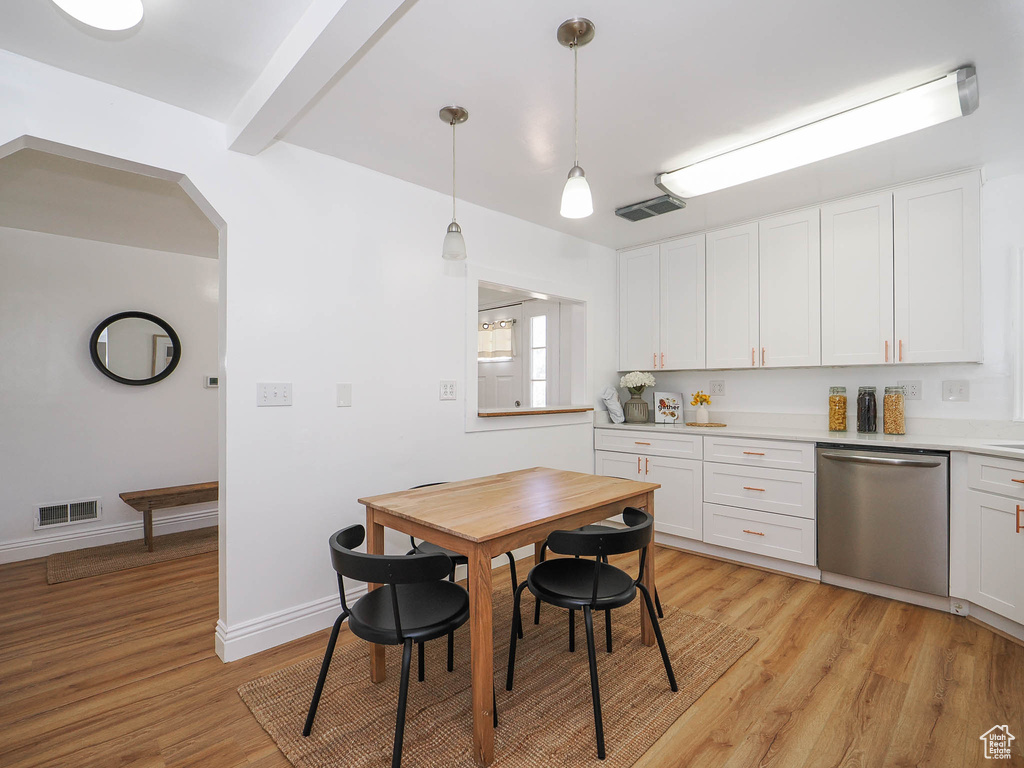 Kitchen featuring white cabinetry, stainless steel dishwasher, light hardwood / wood-style flooring, and pendant lighting