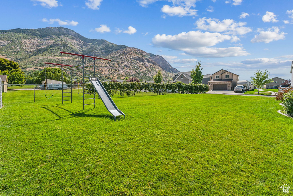 View of yard with a garage, a mountain view, and a playground