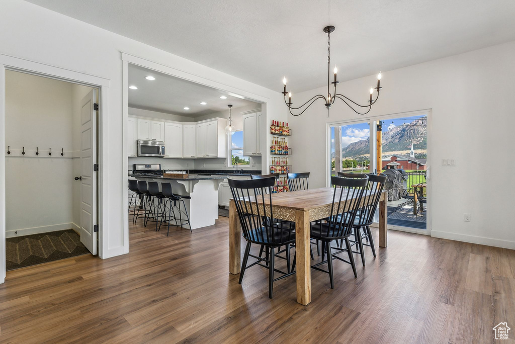 Dining area featuring sink, an inviting chandelier, and dark hardwood / wood-style flooring