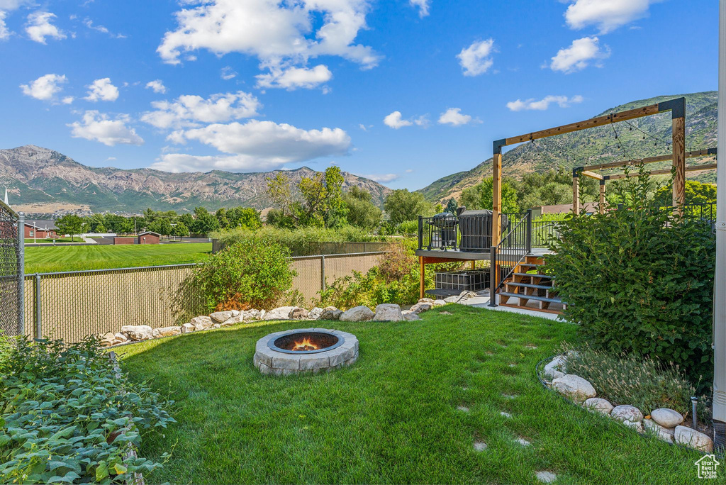 View of yard featuring a deck with mountain view and an outdoor fire pit