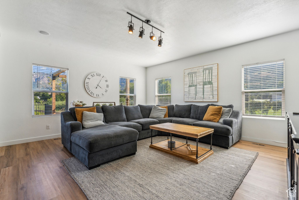 Living room featuring light hardwood / wood-style floors, rail lighting, and a textured ceiling