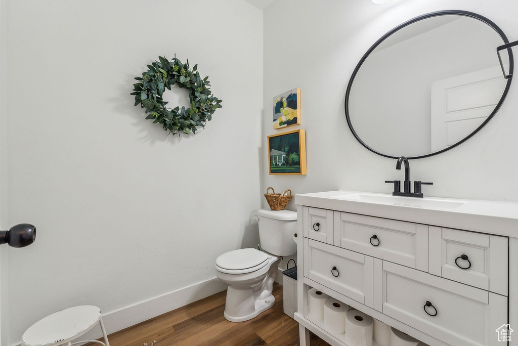 Bathroom with hardwood / wood-style flooring, vanity, and toilet